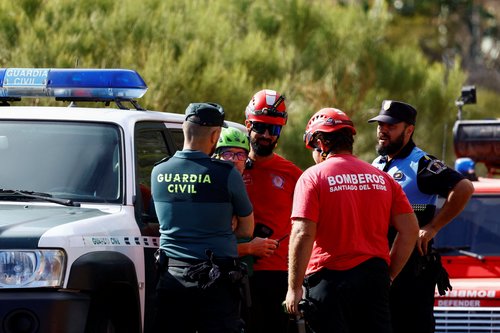 Police officers and firefighters talk during the search for a young British man in the Masca ravine