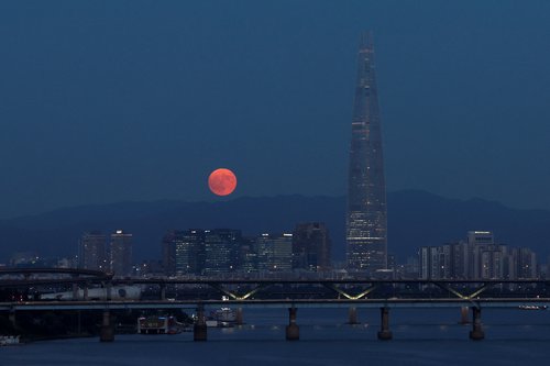 A super moon, known as the Blue Moon, rises next to the 123-story Lotte World Tower in Seoul