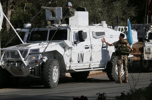 Lebanese army soldier stands near UN peacekeepers (UNIFIL) vehicles in Marjayoun