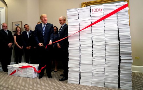 FILE PHOTO: U.S. President Donald Trump cuts a red tape while speaking about deregulation at the White House in Washington