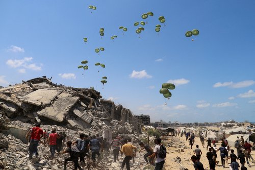 FILE PHOTO: Palestinians run towards parachutes carrying aid packages airdropped over northern Gaza Strip, August 7, 2025. REUTERS/Ebrahim Hajjaj/File Photo