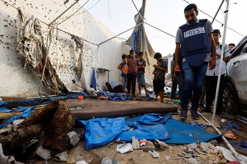 A member of the media inspects the damage at the site of an Israeli strike on a tent near Shifa Hospital where Al Jazeera journalists Anas Al Sharif, Mohammed Qreiqeh, Ibrahim Zaher, and Mohammed Noufal were killed, in Gaza City
