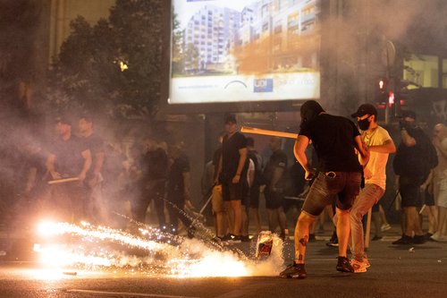 People react next to exploding fireworks, during a standoff between supporters of the ruling party and anti-government protesters in Belgrade, Serbia, August 14, 2025. REUTERS/Djordje Kojadinovic