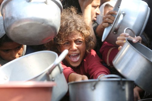 FILE PHOTO: A child reacts surrounded by pots as Palestinians wait to receive food from a charity kitchen in Khan Younis, southern Gaza Strip, August 21, 2025.