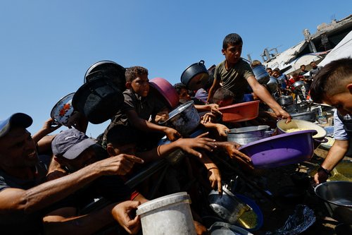Palestinians wait to receive food from a charity kitchen