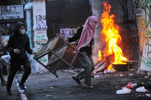 Protesters carry items to be burned outside the regional parliament building during a protest against the government's spending priorities