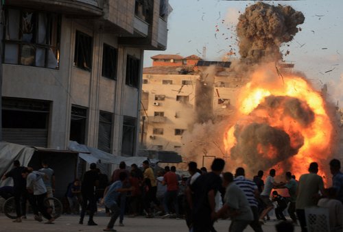 Palestinians react, as smoke and flames rise while a residential building collapses after an Israeli air strike, in Gaza City, September 7, 2025. REUTERS/Dawoud Abu Alkas