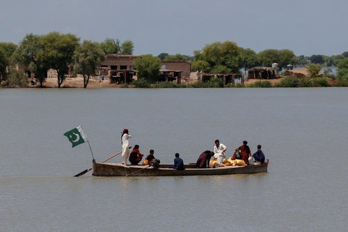 Residents travel on a boat with their supplies, through a flooded area, following monsoon rains and rising water levels of the Indus River, in Ghano Khan Jatoi village in Dadu district, Sindh province, Pakistan