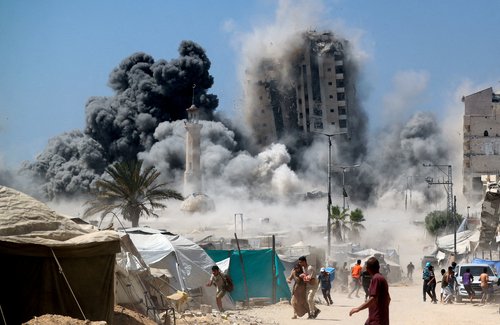 Palestinians run as the 15-storey Mushtaha Tower collapses after being hit by an Israeli air strike, in Gaza City