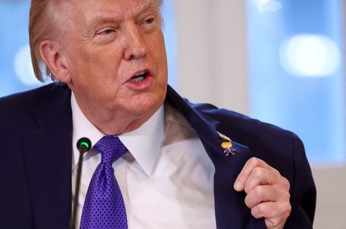 FILE PHOTO: U.S. President Donald Trump displays what he called a "Happy Trump" pin, as he attends a meeting with oil industry executives, at the White House in Washington, D.C., U.S., January 9, 2026.