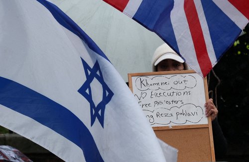 A demonstrator holds a placard among flags outside the Iranian embassy during a rally in support of nationwide protests in Iran, in London, Britain