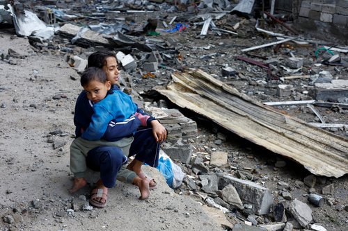Palestinian children sit at the site of Thursday's Israeli strike on a house, in the central Gaza Strip, January 9, 2026.