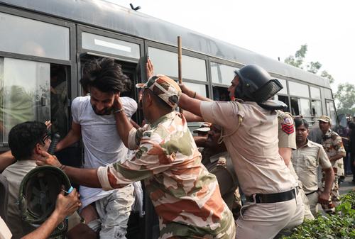 Security personnel try to stop a protester trying to get off the police bus. REUTERS/Priyanshu Singh