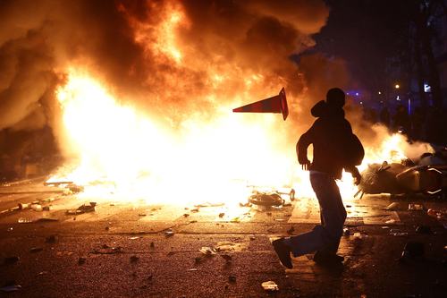A protesters sit on chairs from a vandalized shop as they block a street amid clashes during a day of demonstrations against the cost of living and rising fuel prices in Paris as part of nationwide protests called by the "Yellow Vests" movement