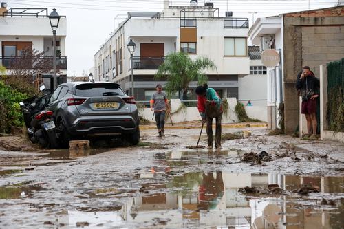 A woman works to clear mud off a road, following torrential rains, which caused floods in eastern Spain, in Els Poblets, Spain, October 19, 2026. REUTERS/Eva Manez