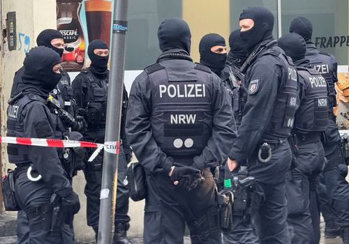 Police officers stand in front of a house during a raid in Cologne. REUTERS/Stephane Nitschke