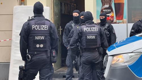 Police officers stand in front of a house during a raid in Cologne, Germany, October 8, 2026. Picture taken with a mobile phone. REUTERS/Stephane Nitschke