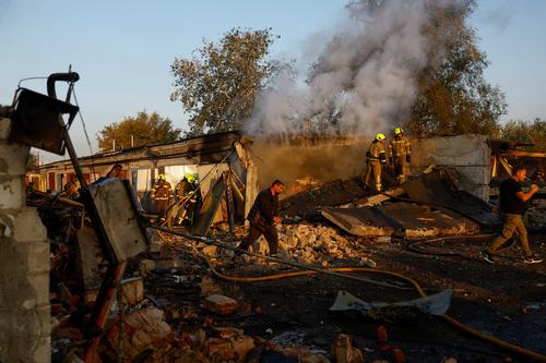 Firefighters work while residents walk past the site of private car garages hit by a Russian missile strike, amid Russia's attack on Ukraine, in Kyiv, Ukraine October 7, 2026. REUTERS/Valentyn Ogirenko