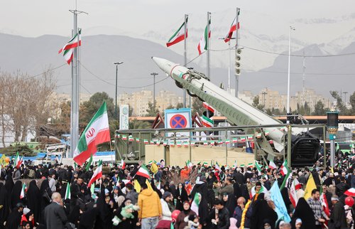 People gather near a missile on display during the 47th anniversary of the Islamic Revolution in Tehran