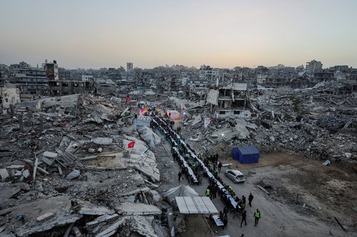 Palestinians gather to break their fast by eating Iftar meals on the first day of the holy month of Ramadan, near the rubble of residential buildings destroyed during the two-year Israeli offensive
