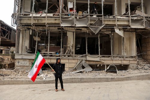 A man holds an Iranian flag following an Israeli and the U.S. strike on Gandhi Hotel Hospital, amid the U.S.-Israel conflict with Iran