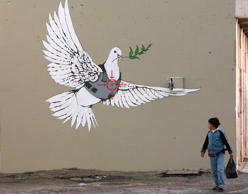 FILE PHOTO: A Palestinian boy looks at one of six new images painted by British street artist Banksy as part of a Christmas exhibition in the West Bank town of Bethlehem December 2, 2007. REUTERS/Ammar Awad
