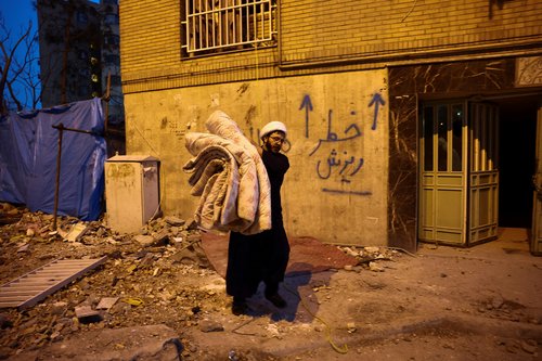 A volunteer carries belongings from one of the damaged houses, which was damaged in a strike, amid the U.S.-Israeli conflict with Iran, in Tehran, Iran, March 18, 2026