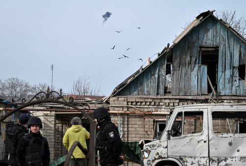 Ukrainian servicemen hit a Russian drone as police officers work at the site of a building hit by a Russian drone strike, amid Russia's attack on Ukraine, in Zaporizhzhia, Ukraine March 21, 2026. REUTERS/Stringer