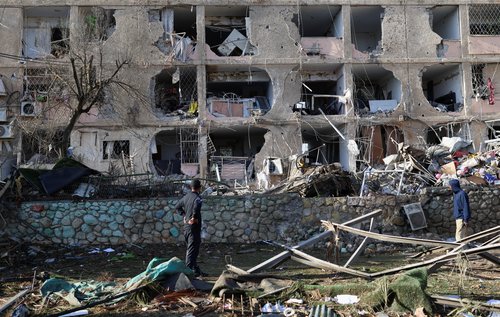 People stand near a damaged building and debris following a night of Iranian missile strikes which injured dozens of Israelis, amid the U.S.-Israel conflict with Iran, in Dimona, southern Israel March 22, 2026. REUTERS/Ronen Zvulun