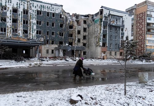 FILE PHOTO: A woman walks past a building damaged by a Russian military strike in the town of Pokrovsk