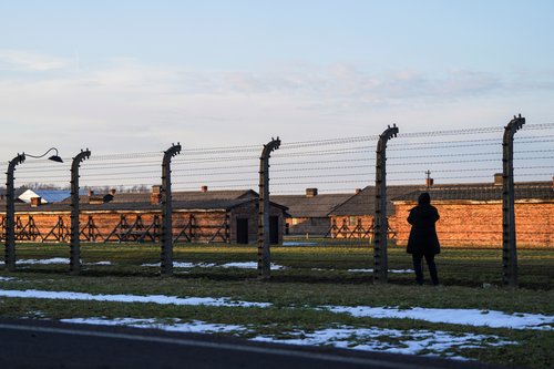 A person stands next to barbed wire at the site of the former Nazi German concentration and extermination camp Auschwitz-Birkenau