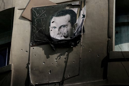 FILE PHOTO: A picture of Bashar al-Assad, damaged by bullets, hangs on the wall of a burnt building of Criminal Security department, after Syria's Bashar al-Assad was ousted, in Damascus