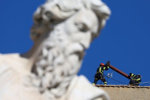 Firefighters work to set a chimney on the roof of the Sistine Chapel, ahead of the conclave, at the Vatican