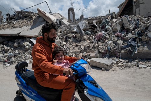 Mhamed, 34, and Taline 2,5 years old, ride a motorcycle past buildings damaged by an Israeli strike in Mansouri village, southern Lebanon, amid a 10-day ceasefire between Lebanon and Israel, April 21, 2026.