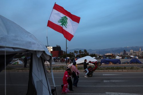 A man rides a motorcycle as displaced people walk at a makeshift encampment amid a temporary ceasefire between Lebanon and Israel, in Beirut, Lebanon, April 24, 2026.