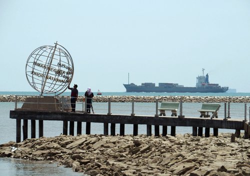 FILE PHOTO: A container ship enters the Singapore Strait for the Strait of Malacca, as tourists stand at mainland Asia's southern most point in Johor, Malaysia November 12, 2016.