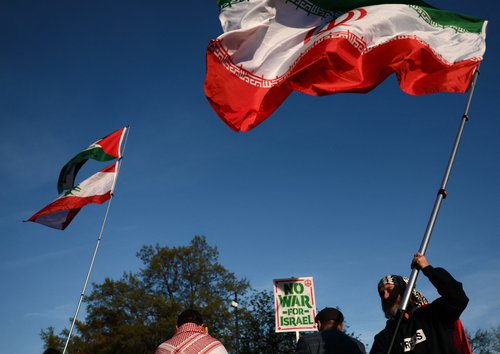 Demonstrators wave flags as they protest against military action in Iran near the White House