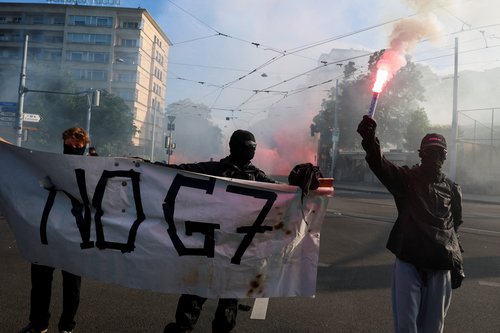 Demonstrators hold a banner and a flare, during a protest against the upcoming G7 summit in Evian-les-Bains in France, in Geneva, Switzerland, June 14, 2026. REUTERS/Denis Balibouse