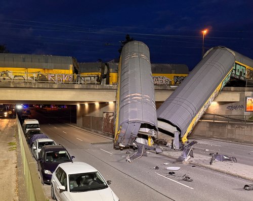 Two cars of a freight train which derailed after a collision, fell off a bridge and lay on a road in Munich, Germany, June 20, 2026. Picture taken using a mobile phone. REUTERS/Christine Uyanik TPX IMAGES OF THE DAY