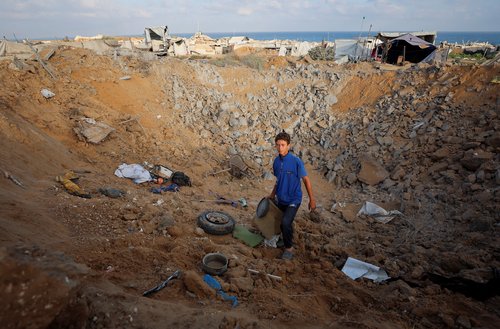 A boy looks on as Palestinians inspect the site of an Israeli strike on a tent camp sheltering displaced people, who were warned to evacuate before the attack, in Gaza City, June 24, 2026.