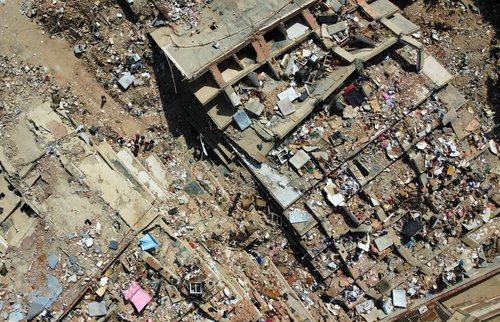 A drone view shows people standing amidst the rubble of a building destroyed by earthquakes, in La Guaira, Venezuela, June 28, 2026.
