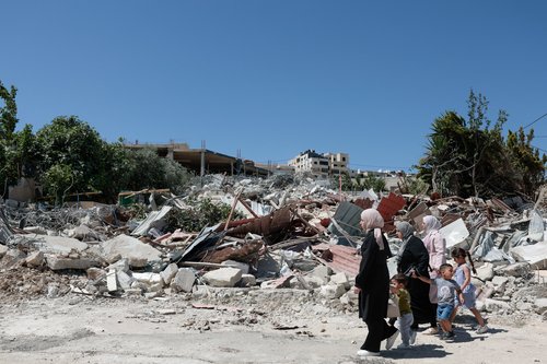 People walk past the rubble of a Palestinian building demolished by Israeli military in the town of Jabaa in the Israeli-occupied West Bank, near Jerusalem