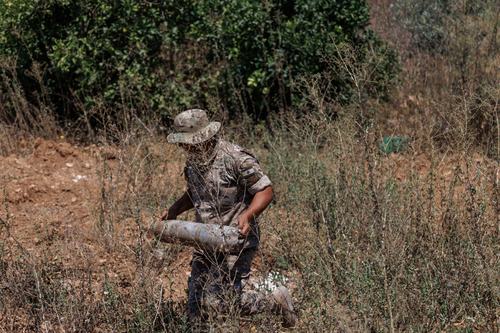 A Lebanese army officer carries an empty shell casing found in a field belonging to a farmer who said it was bulldozed by the Israeli army in Zawtar al-Gharbiyeh