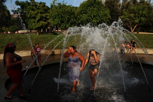Rebeca Guzman and Jhanines Rivera cool off in a fountain at Madrid Rio park during a heatwave in Madrid, Spain, July 8, 2026. REUTERS/Susana Vera