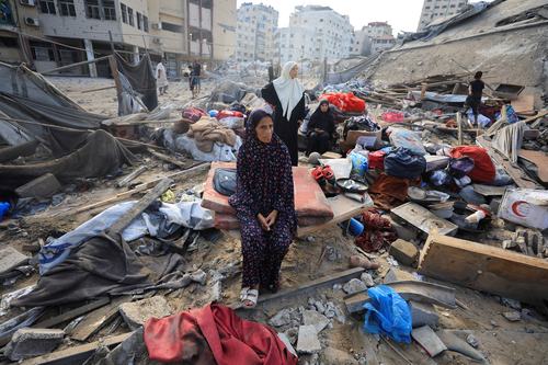 A Palestinian woman sits amidst debris as people inspect the site of Wednesday's Israeli strike on a house whose residents were pre-warned by the Israeli military to evacuate, in Gaza City, July 30, 2026.