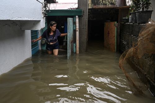 Linda Dawayon exits her flooded house after a heavy overnight rain in Barangay Marulas, Kawit, Cavite, Philippines, August 9, 2026. REUTERS/Noel Celis
