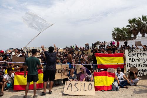 Migrants hold Spanish flags and signs calling for asylum. REUTERS/Maria Alejandra Cardona