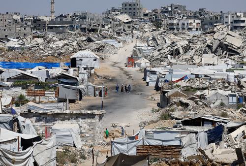 People walk at a site destroyed during the Israeli offensive. REUTERS/Mahmoud Issa