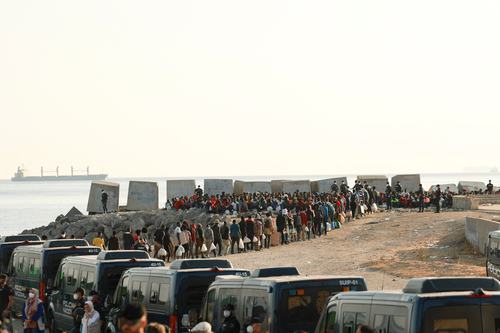Migrants gather near a makeshift beach camp to be relocated to official shelters across the city after authorities cleared the site, following a mass crossing from Morocco, in Spain's North African enclave of Ceuta, August 20, 2026.