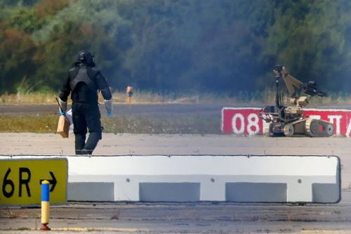 A police officer in protective clothing walks next to an explosive-disarming robot. REUTERS/Axel Schmidt/File Photo